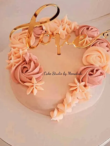 Love is sweet. This pretty anniversary cake features a 'Love' topper and is decorated with hand-piped buttercream rosettes in lovely shades of peach and pink.