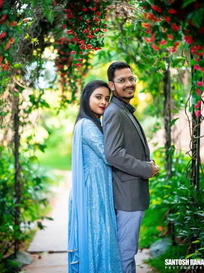 A beautiful portrait of a couple framed by an arch of vibrant red flowers.