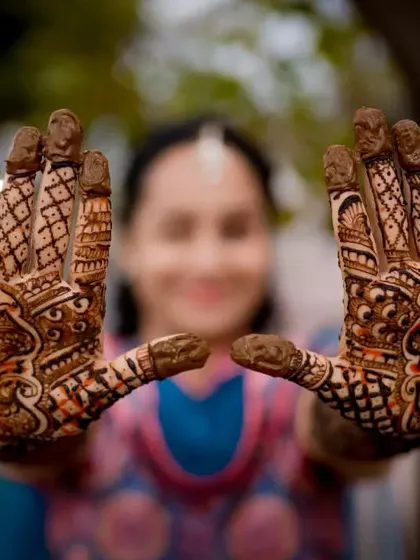 A close-up shot focusing on the bride's hands, showcasing the beautiful and detailed Mehendi art.