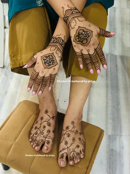 A complete engagement mehendi look, with matching designs on hands and feet. The hands feature the couple's initials 'A' and 'S' in a unique block design.