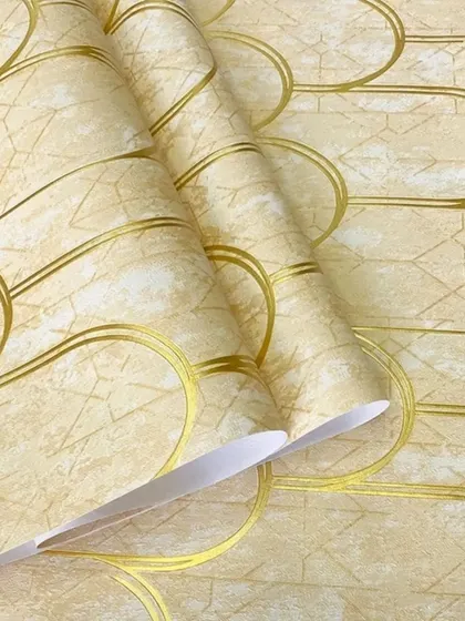 A close-up of a light beige wallpaper with a textured background and a repeating art deco-style scallop pattern in gold.