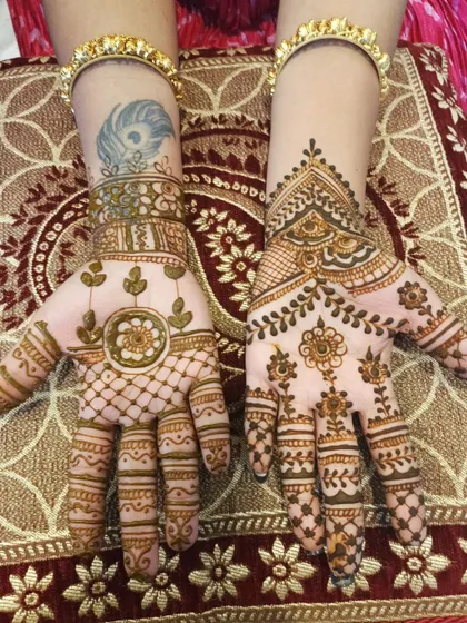 This design shows how mehendi can be applied around an existing tattoo. The patterns are light and airy, featuring floral and leafy motifs that complement the client's own art.