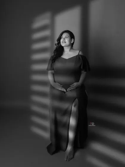 A classic black and white portrait with beautiful window-like shadows. This technique adds depth and artistry to a simple and elegant maternity shot.