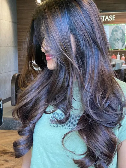 This image captures the beautiful texture of a layered cut styled with soft curls. The layers create dimension and prevent the hair from looking flat.