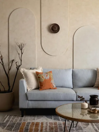 This living room is an exercise in subtle elegance. I used a textured lime wash on the walls with minimalist arched grooves to create a soft, sculptural effect. The powder blue sofa and earthy decor pieces add warmth and comfort, making the space feel calm and inviting.