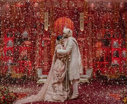 The Jaimala moment, where the couple is showered with petals inside the breathtaking 'Lal Bagh' setting. This is the culmination of months of planning, resulting in a moment of pure, unscripted joy.