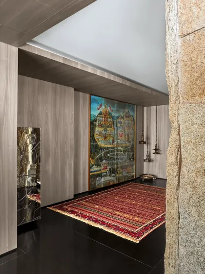 This contemporary mandir space is defined by a 100-year-old 'pat' painting depicting the sacred Jain site of Palitana. Paired with an antique rug from Istanbul and the client's collection of traditional lamps, it creates a deeply personal and sacred atmosphere.