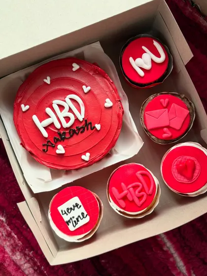A bold red-themed birthday set for Akash. The bento cake is surrounded by six matching cupcakes with various designs like "love mine" and an envelope, making it a complete celebration package.