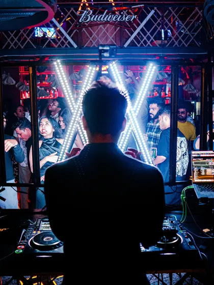 A powerful silhouette shot from behind the decks, with the Budweiser and custom lighting in the background.