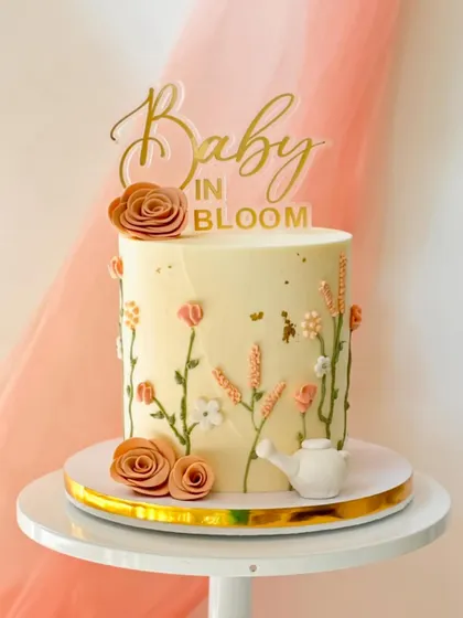 A sweet "Baby in Bloom" cake for a baby shower. This design features delicate, hand-piped wildflowers growing up the side of the cake, complete with a tiny watering can.