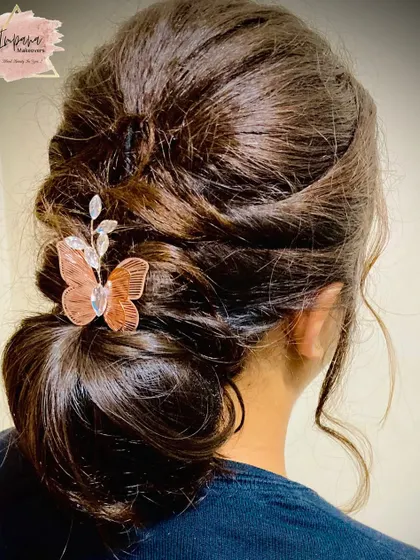 A soft, textured low bun with a butterfly-themed hair accessory. This romantic hairstyle is ideal for an engagement or reception.