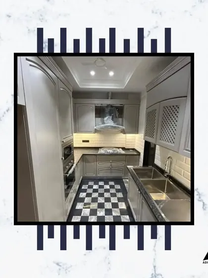 This modern kitchen design features a sleek grey finish, a double sink, and a classic checkerboard floor. It's a space where elevated living meets unparalleled sophistication.