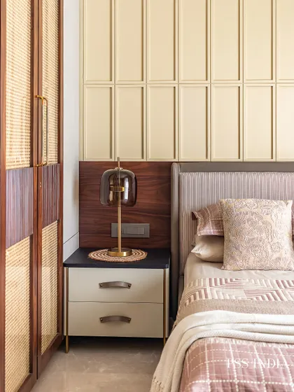 This cozy bedroom is a perfect example of how to blend different materials. The warmth of the rattan-paneled wardrobe is balanced by the soft, layered bedding and the clean lines of the wall paneling.