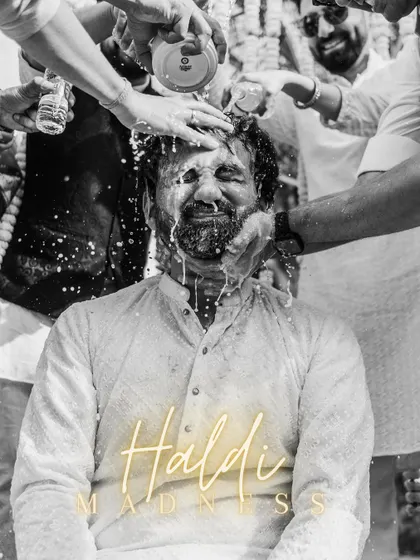 The definition of "Haldi Madness." This black and white shot freezes a moment of pure, unadulterated fun as the groom gets drenched by his friends.