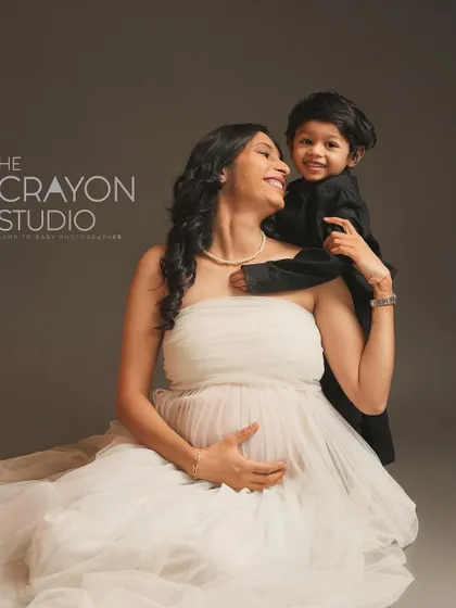 The sweet bond between a mother and her first child as they wait for the new arrival. His happy face peeking over her shoulder is absolutely precious.