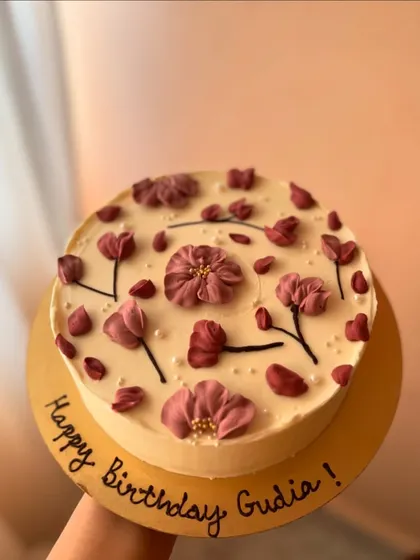 A close-up of the vanilla sponge cake with homemade raspberry jam and white chocolate ganache, decorated with beautiful purple piped flowers.