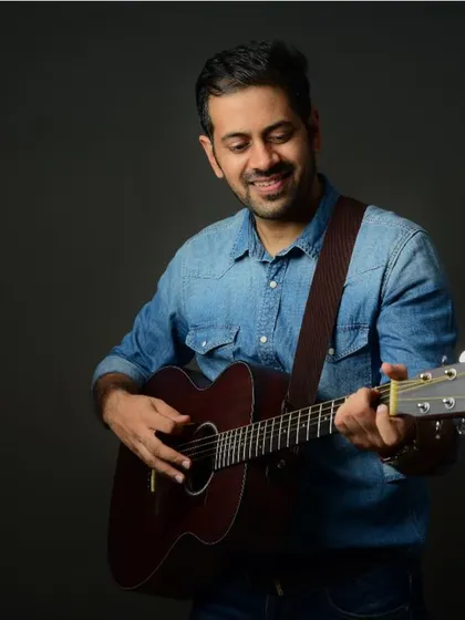 A musician's portrait, capturing the joy of playing the guitar. A genuine smile makes the portrait feel warm and inviting.