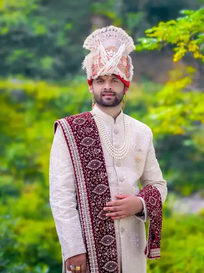 A classic portrait of the groom looking directly at the camera. His traditional attire, from the pearl necklace to the turban, is showcased beautifully.