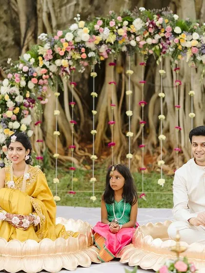 A beautiful family moment during the Haldi ceremony. The decor was designed to be a picturesque frame, with the couple seated in brass lotus urlis under a stunning pastel floral arch.