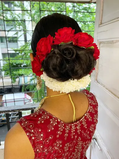 I have a special love for creating intricate floral buns. This traditional look was personalized with vibrant red roses and a gajra of jasmine, making it a stunning centerpiece for her wedding attire.