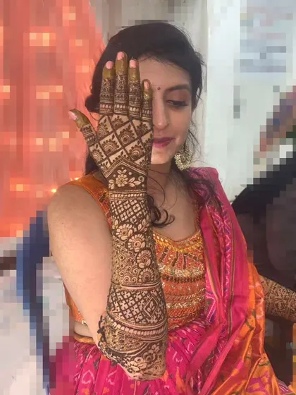 This bride is showcasing her intricate, geometric-patterned bridal mehendi that extends all the way up her arm.