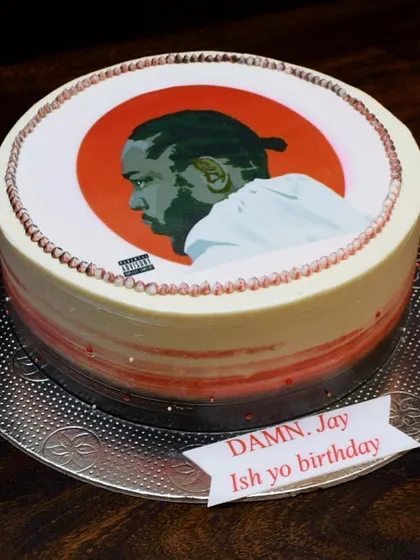 DAMN. A cake for a Kendrick Lamar fan, featuring an edible print of his iconic album cover. The design is complemented by a red and black ombre effect on the sides for a bold, graphic look.