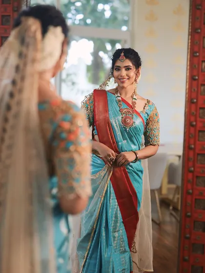 A beautiful shot from a collaboration with a designer. The bride is admiring her reflection, and her makeup is kept soft and elegant to complement the sky-blue saree.