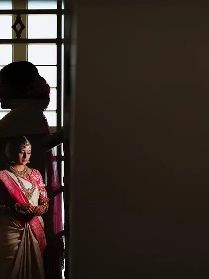 An artistic portrait of the bride, her silhouette reflected in a window, creating a moody and creative image.