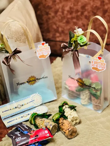 A full display of Rakhi gifts ready for delivery, including clear tote bags and loose items like dry fruit jars and rakhi sets.