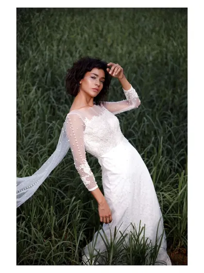 A different pose from the same editorial bridal shoot. The bride's gaze and the elegant lines of her gown create a look of quiet confidence and modern grace.