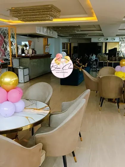 Pastel balloon centerpieces on tables in a modern restaurant setting.