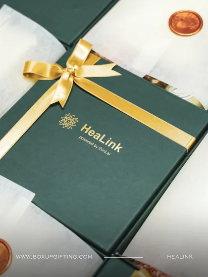 A custom branded gift box for HeaLink. The deep green box paired with a gold ribbon and logo creates a premium feel, perfect for high value client gifting or special corporate events.