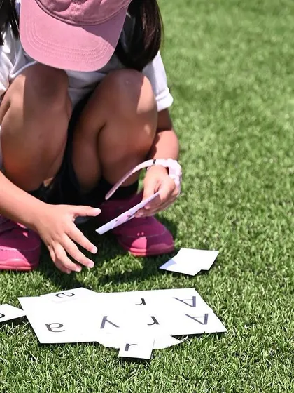 Another child completes a name puzzle on the grass, a fun and personalized challenge.