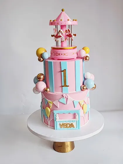 Another look at the stunning pink and blue carousel cake. The details, like the ticket booth and bunting, bring the carnival theme to life.