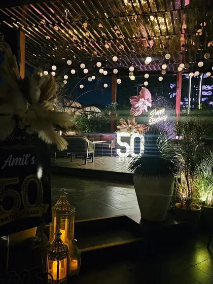 Another angle of the rooftop 50th birthday setup. The combination of the wooden deck, string lights, and the sparkling backdrop creates a perfect blend of rustic and glam.