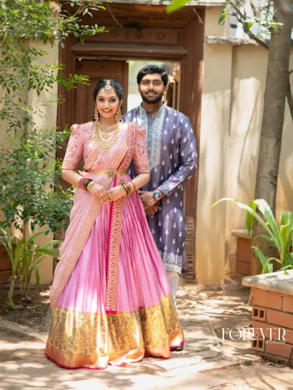 Here, the groom wears a custom purple kurta with delicate silver embroidery around the neckline. The color was chosen to coordinate with the bride's magnificent pink Kanchi lehenga, creating a visually stunning pair.