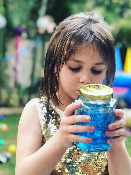 A moment of quiet wonder amidst the party fun. This guest is examining her "ocean in a jar," a sensory craft activity that also serves as a beautiful, themed party favor.