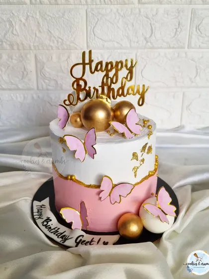 A pretty pink and white cake with gold accents and delicate butterflies. This is a classic feminine design that's perfect for birthdays.