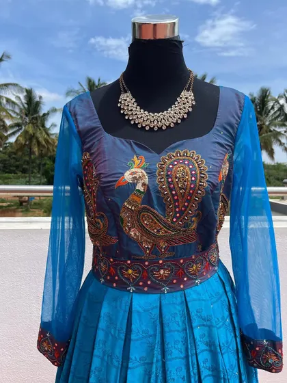 A blue gown with a peacock embroidered bodice and sheer sleeves.