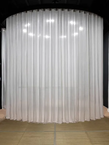 The cylindrical display pod is shown here fully shrouded by sheer white curtains. This 'veiled' state conceals the product, building anticipation and transforming the act of shopping into a moment of gradual, controlled revelation.