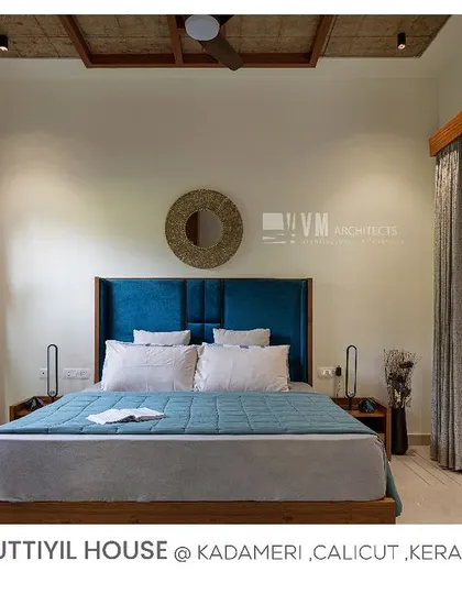 This bedroom at Kuttiyil House is a perfect blend of modern comfort and traditional aesthetics, with its blue headboard and dual windows opening to green courtyards.
