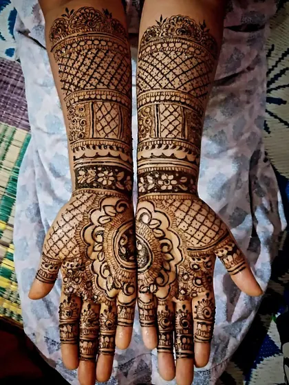 A traditional design with a large central mandala. The arm is covered with bands of different patterns, including jaal (net) and floral designs.