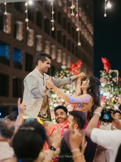 The couple is lifted onto the shoulders of their friends and family as they dance together during a high-energy Sangeet night.