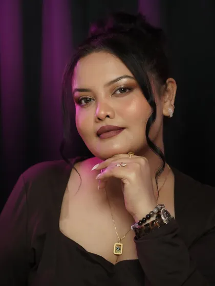 A confident and powerful pose. The makeup is flawless, with a matte brown lip and a subtle shimmer on the eyes, suitable for both day and night.