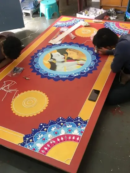 Two of our team members working on the final touches of a large, custom Lippan art piece. This shows the hands-on nature of our work.