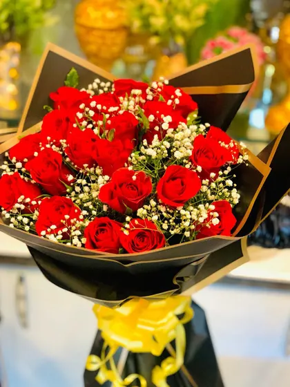 A classic bouquet of red roses and baby's breath in a sophisticated black wrap with gold edging. The yellow ribbon adds a pop of color to this timeless arrangement.