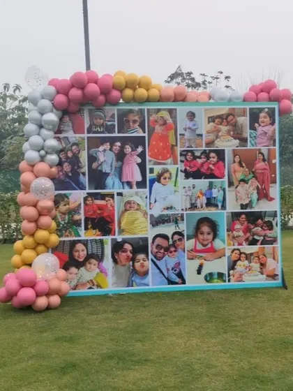 A wide shot of the photo collage backdrop, showing how it can be a central feature for an outdoor party. The balloon garland adds a festive frame to the display.