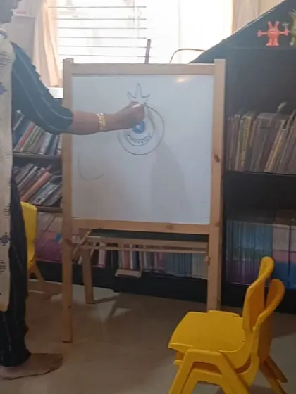 The storyteller adds details to the monster drawing, showing the children how to add personality to their creations.