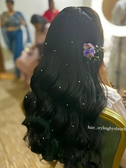 A simple half-up style with classic waves, adorned with scattered pearls and a small floral clip on the side. This is a delicate and pretty option for any festive occasion.