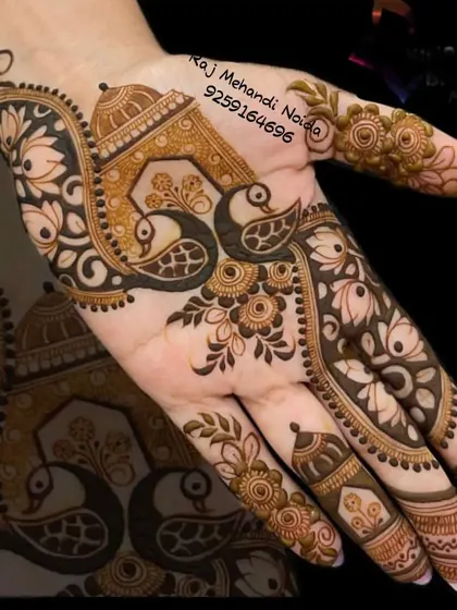 This design beautifully incorporates two peacocks under a traditional arch, creating a lovely symmetrical look on the palm. The surrounding floral and paisley patterns add to its classic charm.